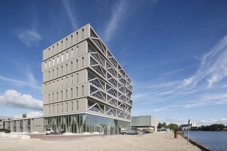 Byggingin var reist á iðnaðarsvæði í Amsterdam og má segja að kveikjan að hönnun hennar og smíði hafi verið efnahagshrunið og hrunið á fasteignamarkaðnum sem varð í Amsterdam og víðar árið 2009.