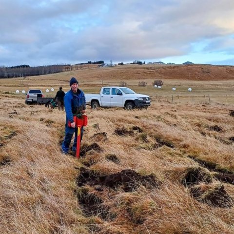 Hrafn Óskarsson, ræktunarstjóri á Tumastöðum, mundar geispuna. Kollabær í baksýn. Ljósmynd: Valgerður Erlingsdóttir