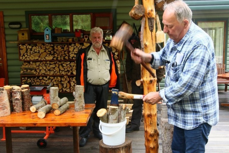 Ólafur sýnir haganlega aðferð við að kljúfa eldivið í fötu svo bitarnir detti ekki á jörðina. Sæmundur Þorvaldsson fylgist með.
