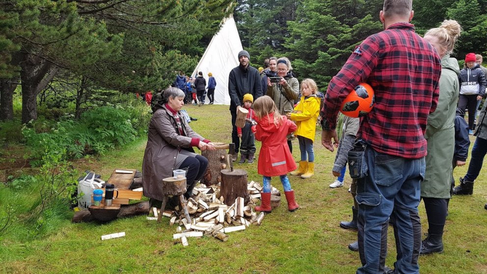 Ung skógarkona spreytir sig á því að kljúfa eldivið með kjullu og öxi. Eygló Rúnarsdóttir leiðbeinir…