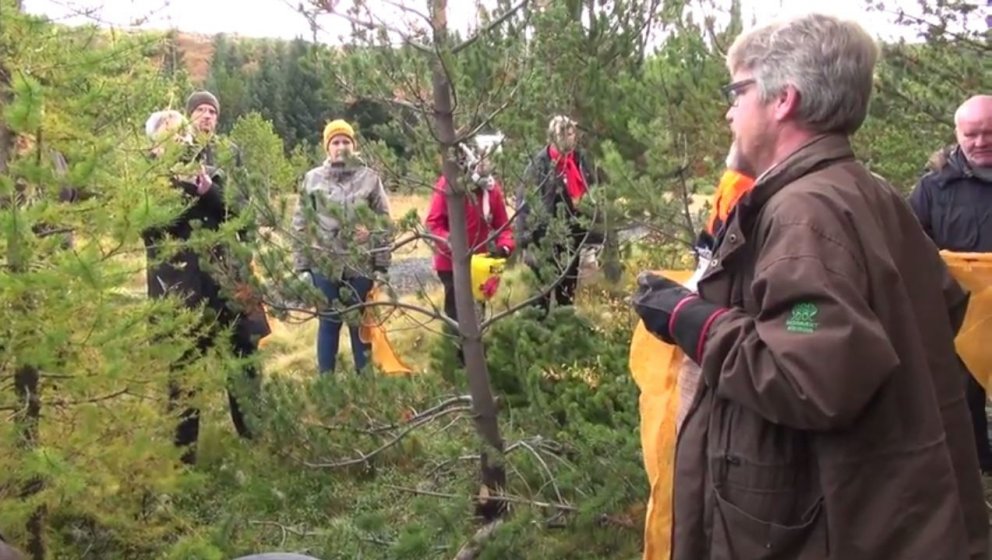 Aðalsteinn sýnir nemendum á námskeiðinu hvernig hengja má poka framan á sig til að auðvelt sé að tín…