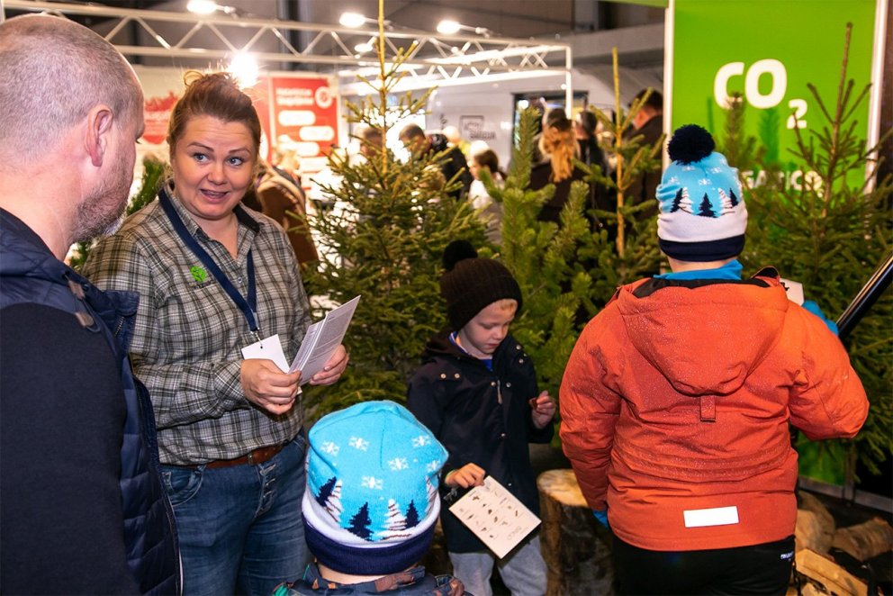 Helena Marta Stefánsdóttir, sérfræðingur og skógræktarráðgjafi, tekur á móti fjölskyldu í bás Skógræ…