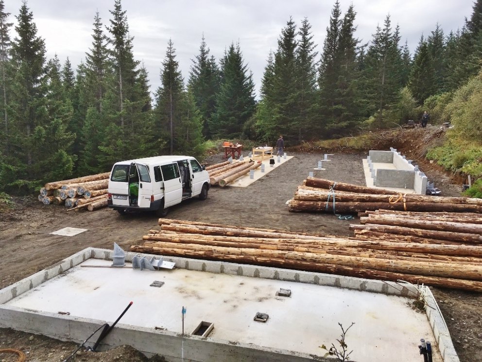 Séð yfir byggingarstaðinn, grunn hússnis og efnið í grindina.
