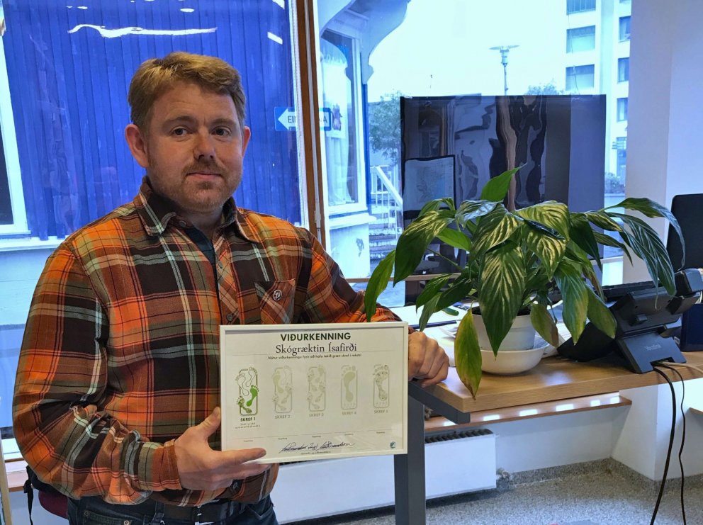 Kristján Jónsson, skógræktarráðgjafi á Ísafirði, með viðurkenningarskjal starfstöðvarinnar þar. Ljós…